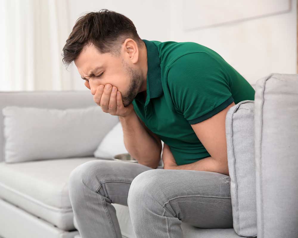 man sitting on the sofa covering mouth nauseous