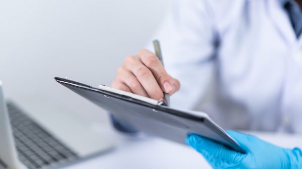 doctor writing on clipboard