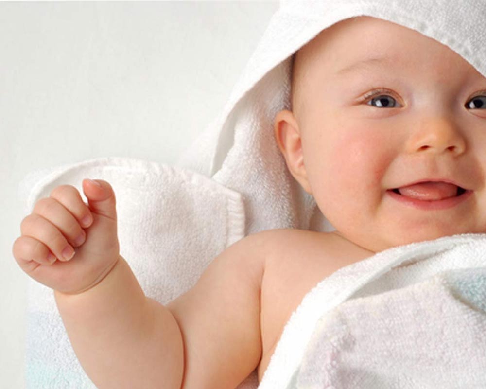 baby smiling wrapped in a white towel