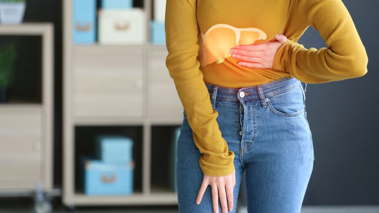 Woman in yellow sweatshirt in pain due to liver inflammation