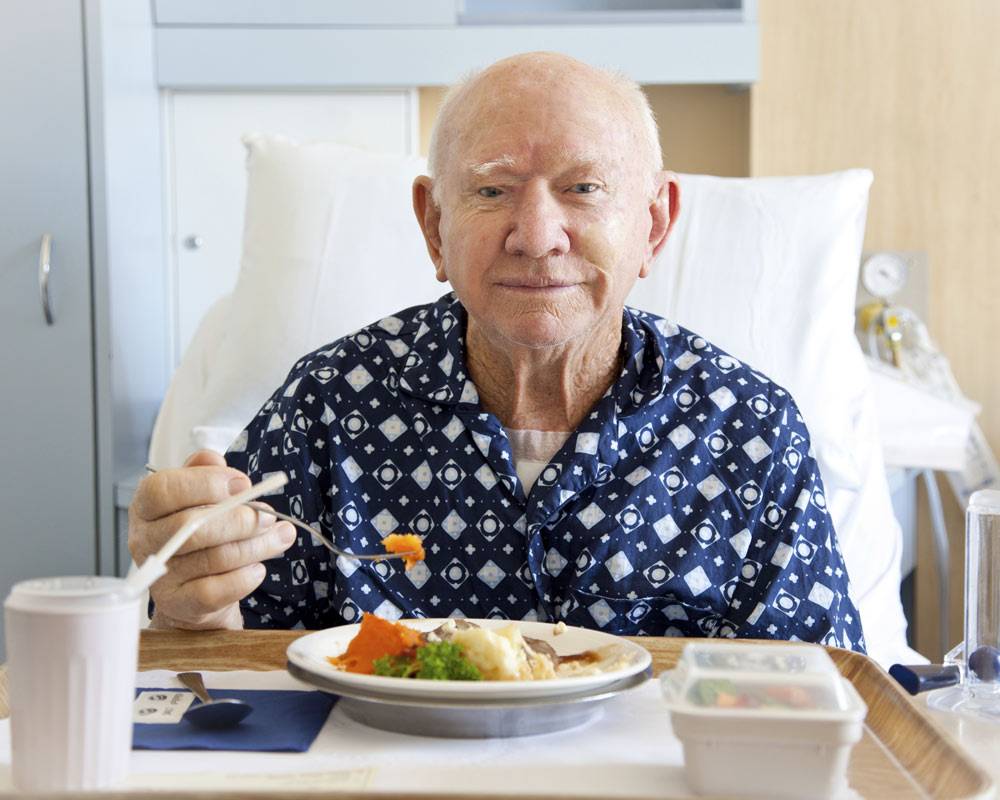 Old man eating on a hospital bed