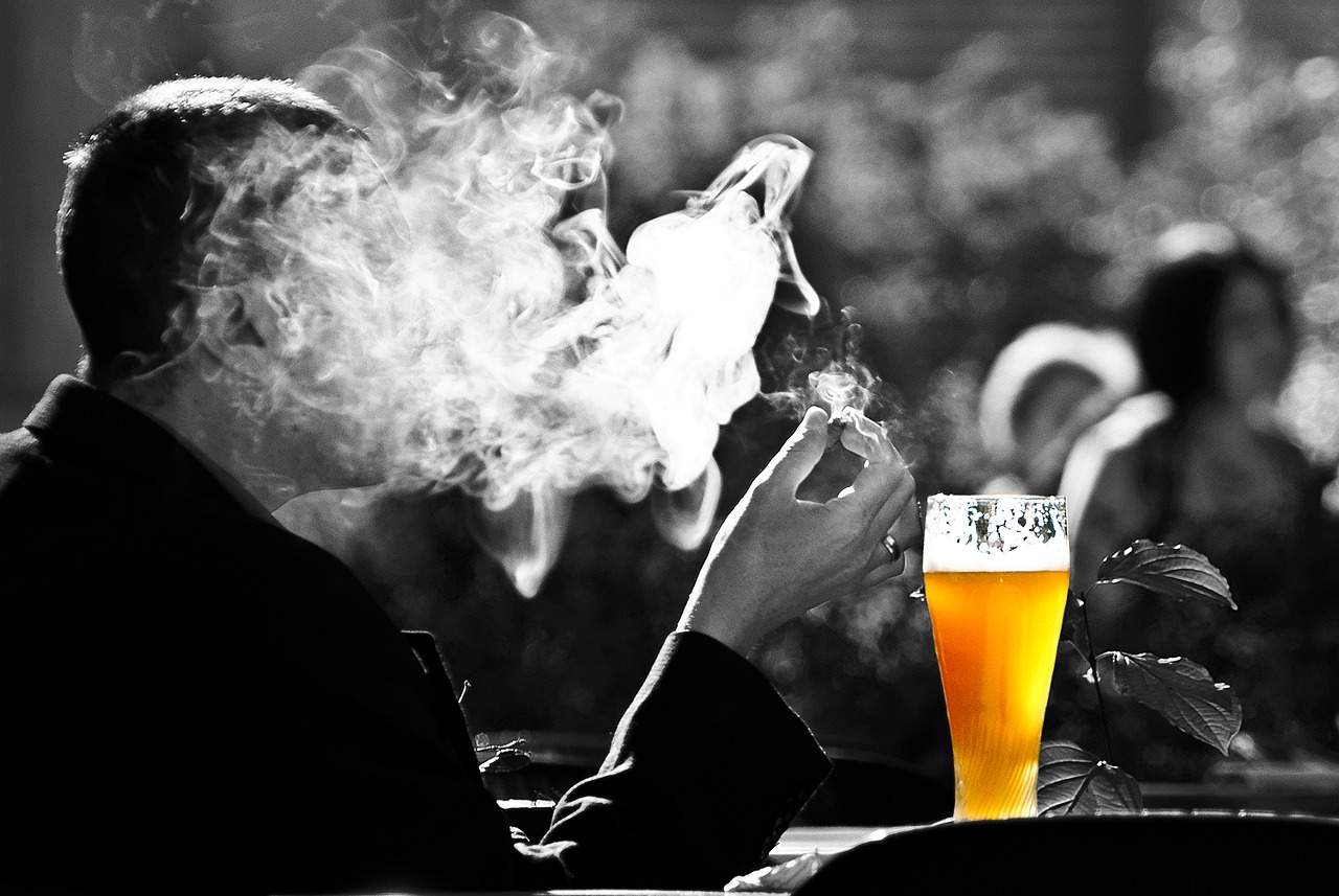 man covered with smoke from cigarette and a glass of beer