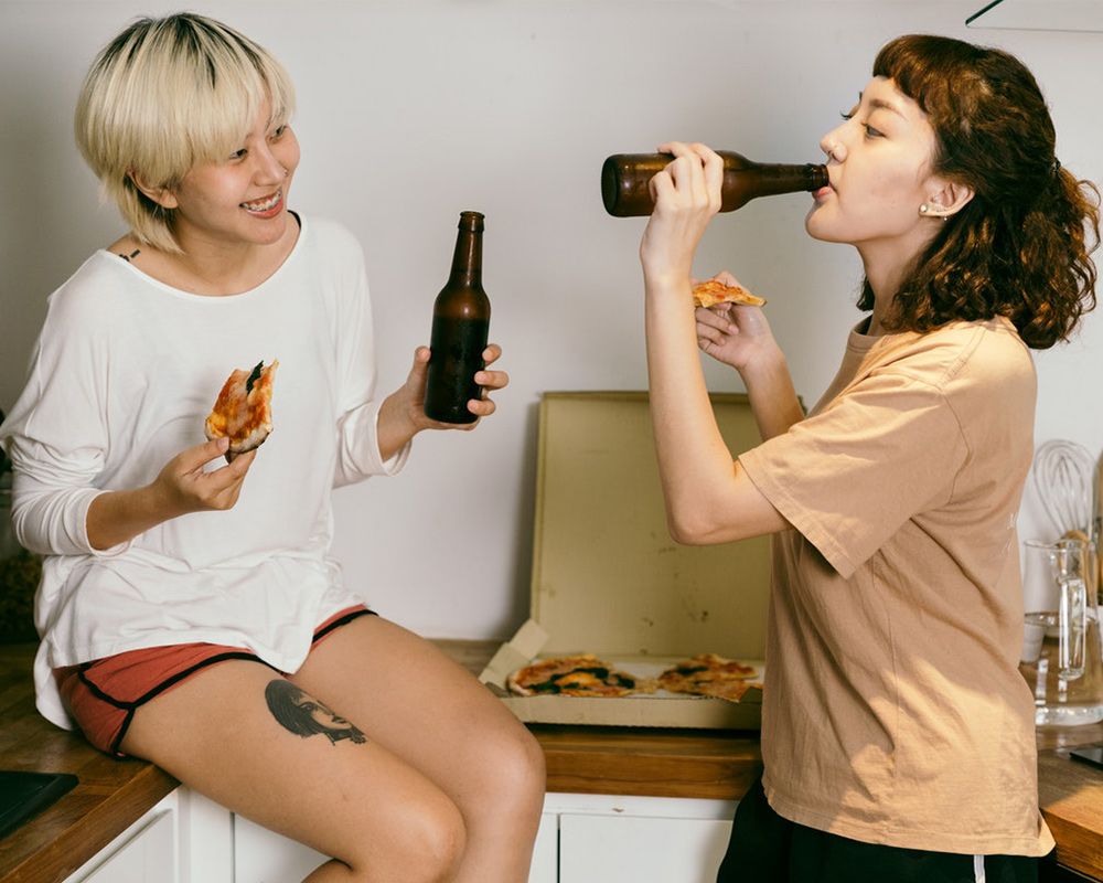 two ladies drinking beer and eating pizza