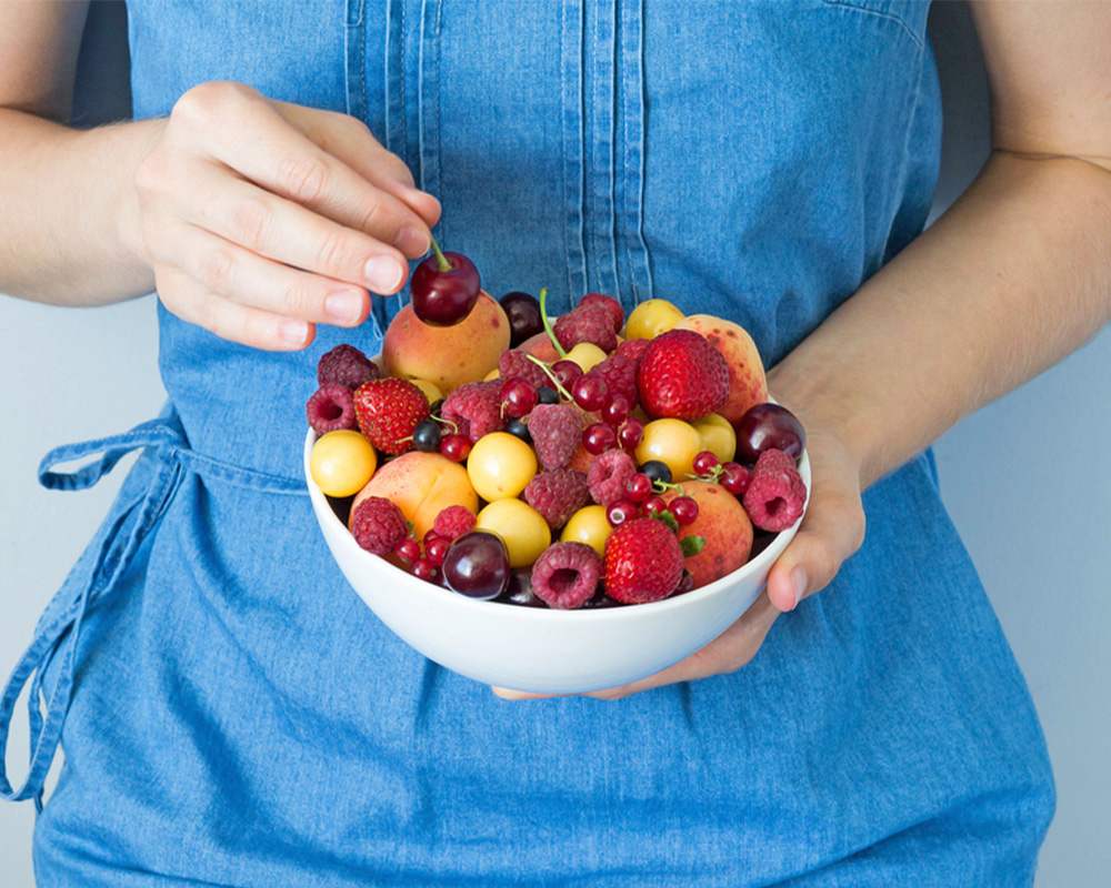 woman holding a bowl of fresh fruit salad