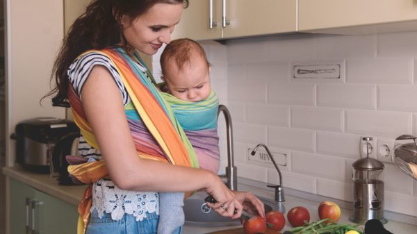 Mom preparing food while carrying baby